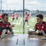 Reunião de equipe do Flamengo com gráficos digitais mostrando dados de desempenho.