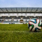 Uma bola de futebol em campo com um estádio vazio ao fundo
