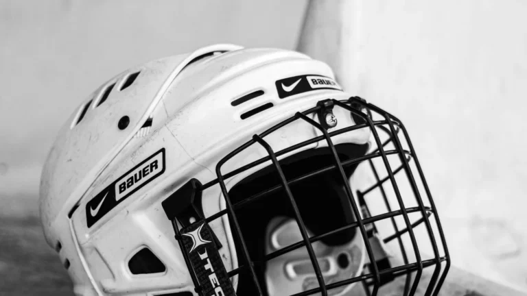 Black and white photo of a hockey helmet on a bench
