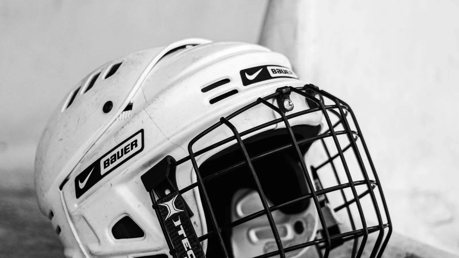 Black and white photo of a hockey helmet on a bench