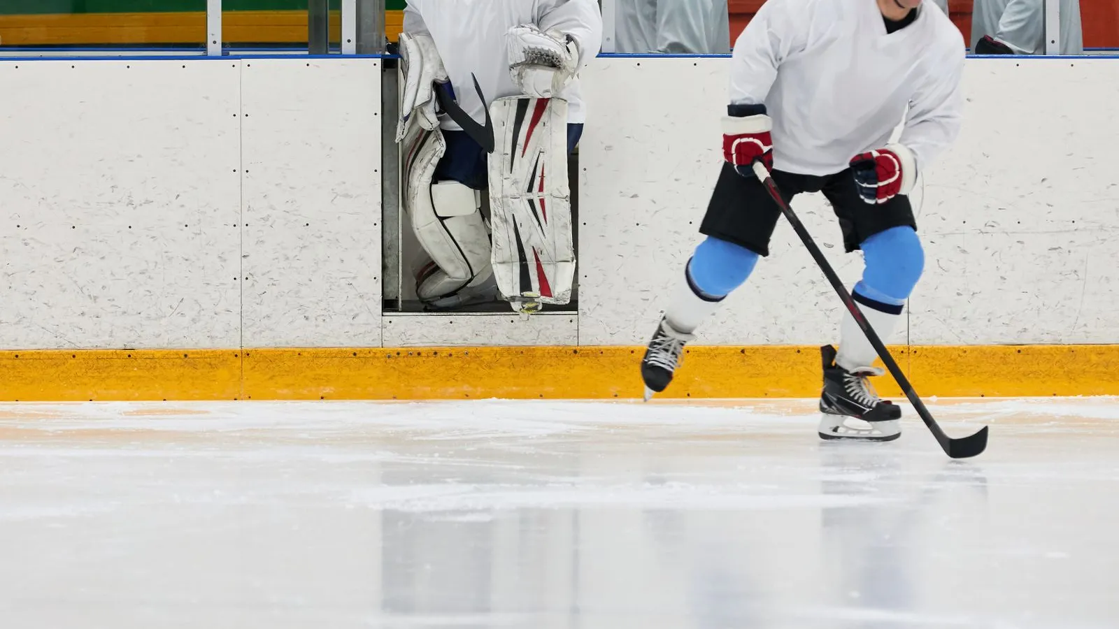 Hockey players in white practice gear on the ice