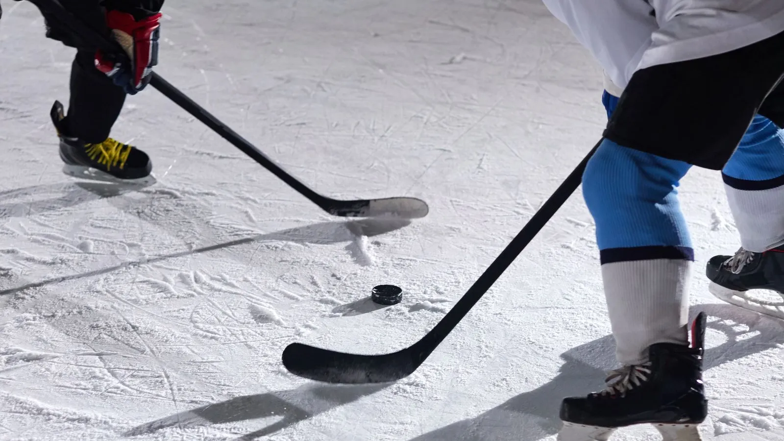 Close-up of hockey sticks and puck on the ice