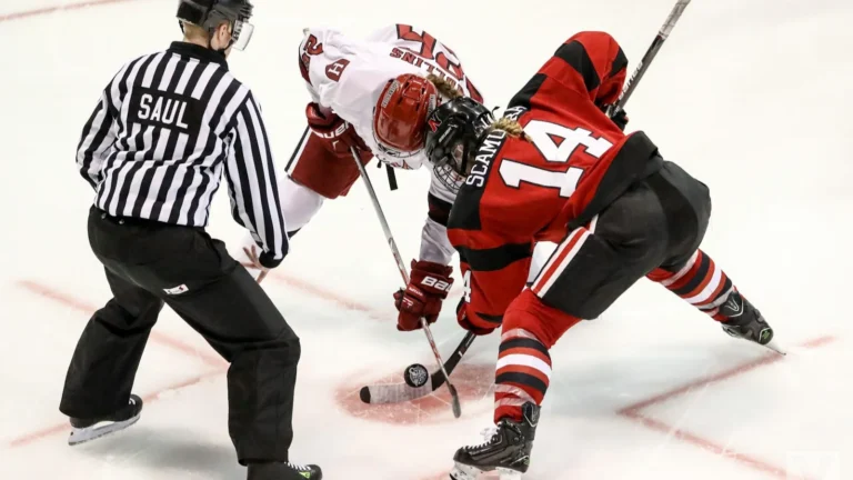 Two hockey players battling in a faceoff as the referee drops the puck